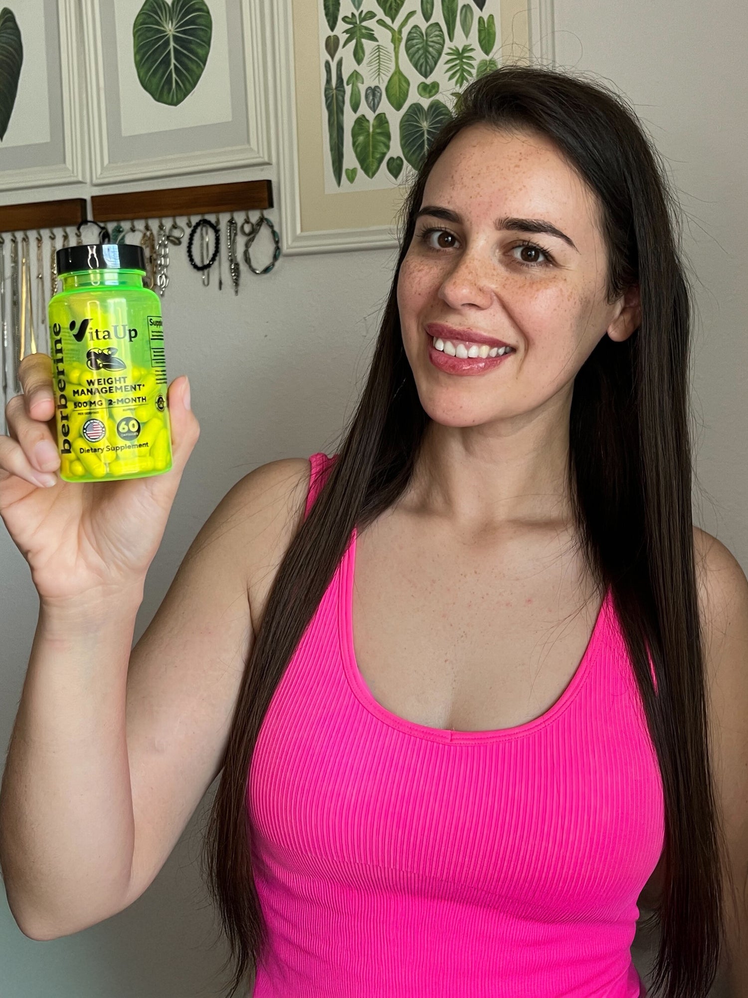 Smiling woman holding a bottle of VitaUp Berberine supplement, highlighting her positive testimonial on weight support, alongside two video previews showing product usage outdoors and close-up shots of capsules.
