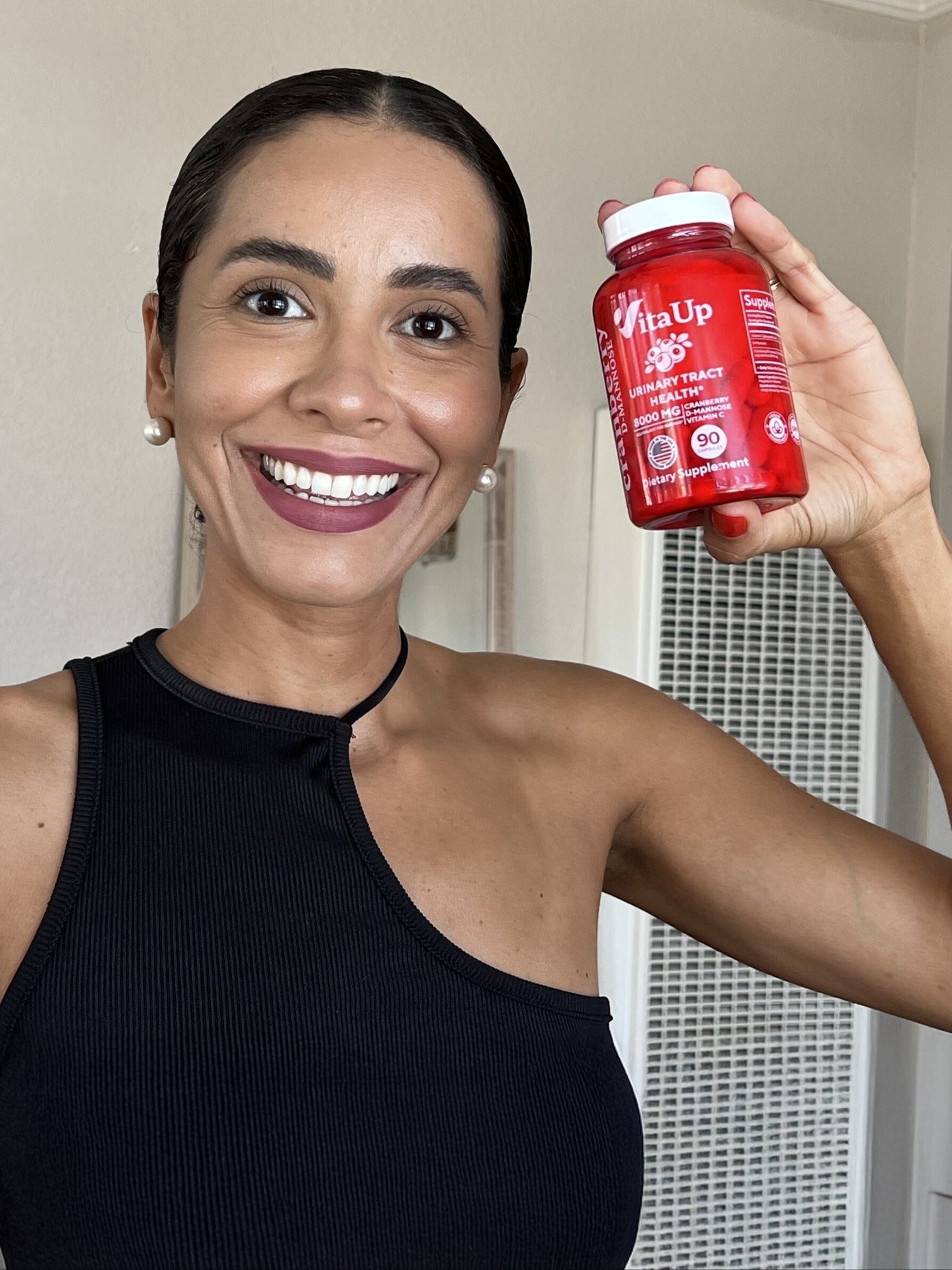 Smiling woman holding VitaUp Cranberry Capsules, showcasing support for urinary tract and immune health.