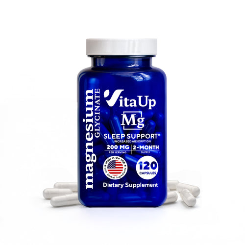 Close-up image of a blue VitaUp Magnesium Glycinate supplement bottle with a white cap, labeled for sleep support with 200mg per serving and 120 capsules, surrounded by a few white capsules on a white background.