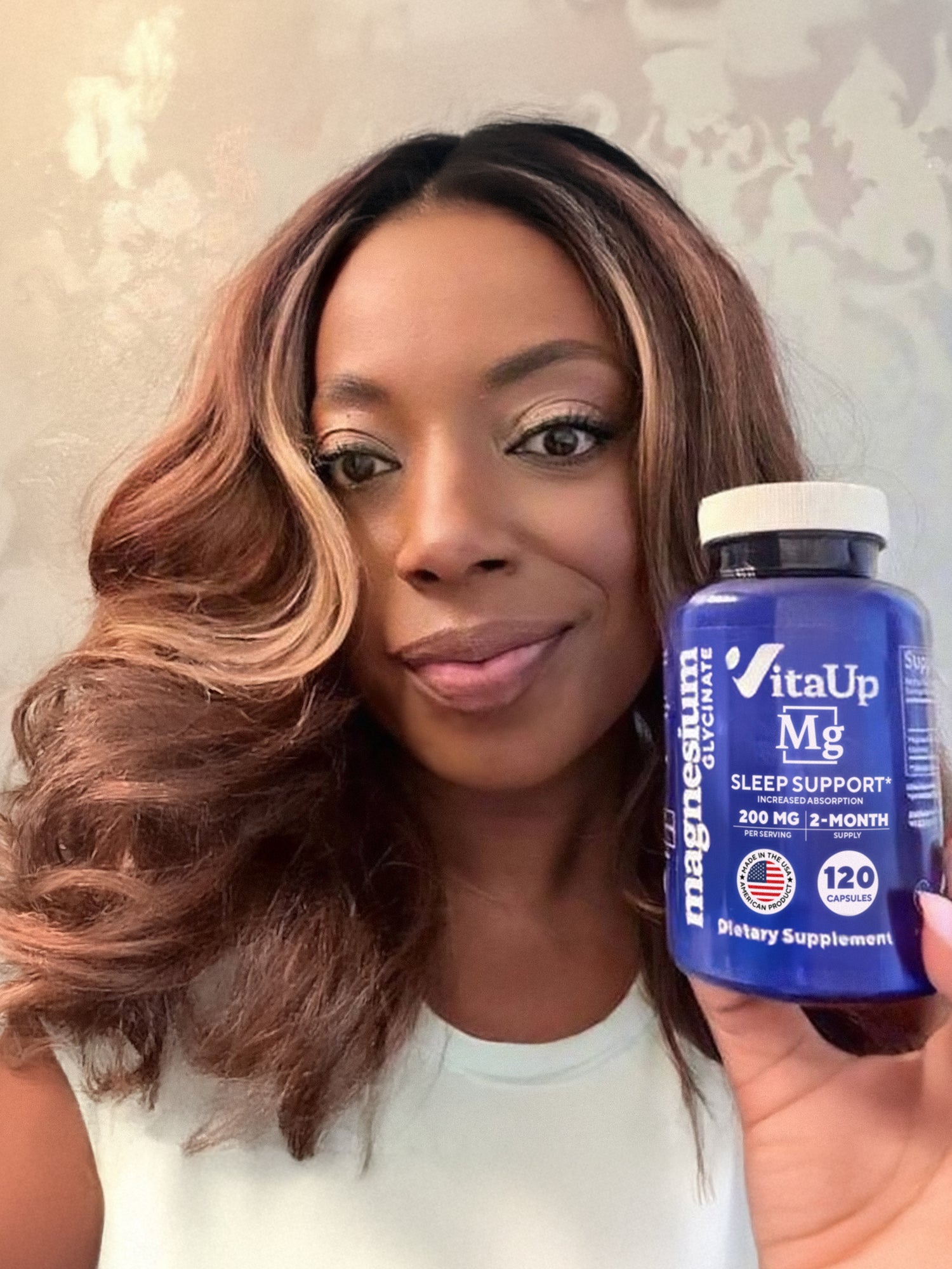 Smiling woman holding a bottle of VitaUp Magnesium Glycinate supplement, promoting improved sleep, muscle relaxation, and metabolic support.