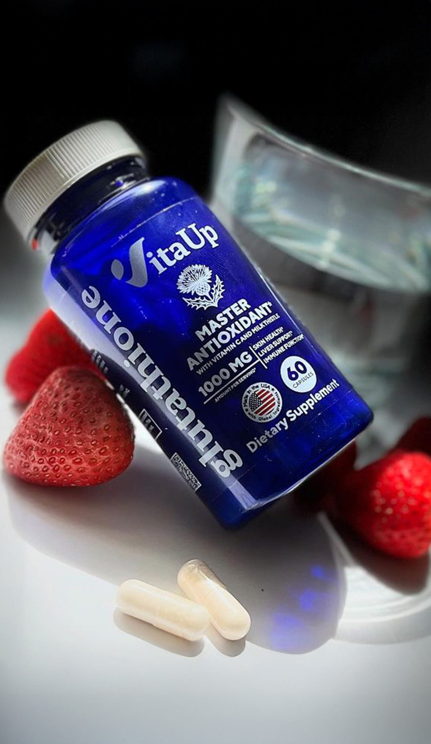 VitaUp Glutathione supplement bottle placed on a glossy surface with strawberries, raspberries, and capsules, highlighting product aesthetics and ingredients.