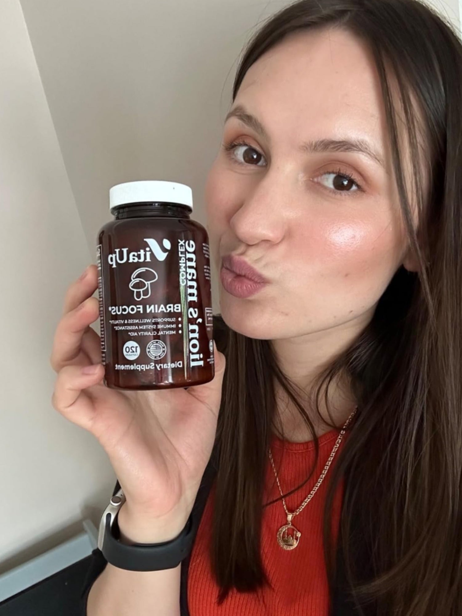 Woman smiling and holding a bottle of VitaUp Lion’s Mane supplement, showcasing satisfaction with the product.