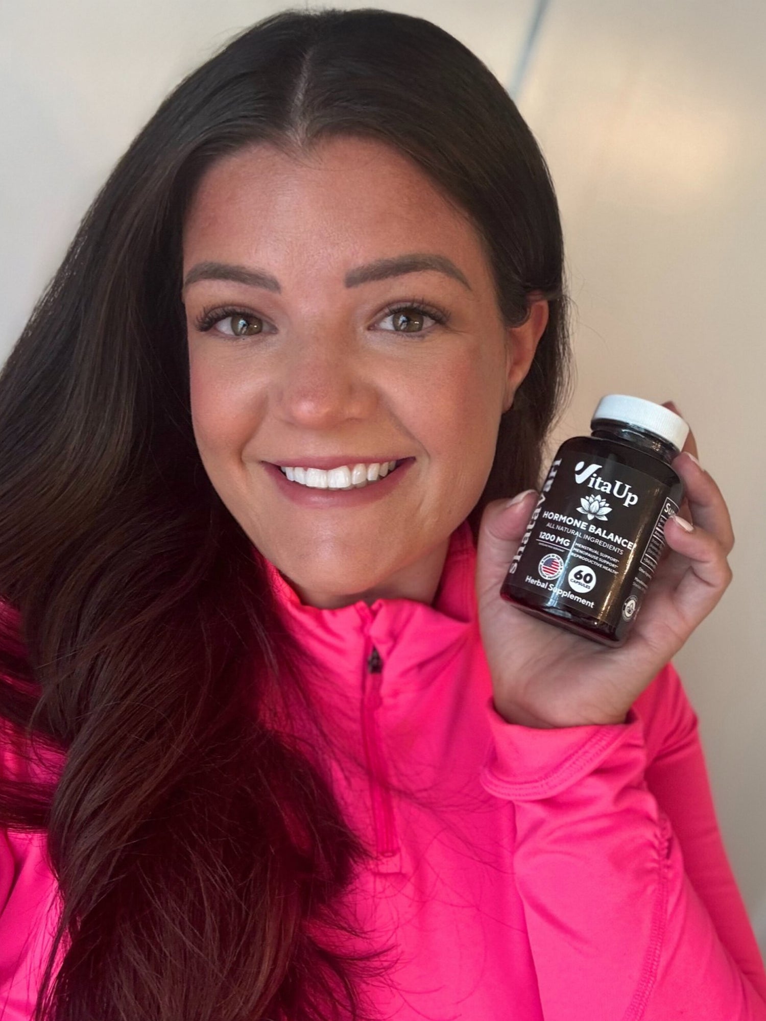 Woman smiling and holding a bottle of VitaUp Shatavari Hormone Balance supplement.